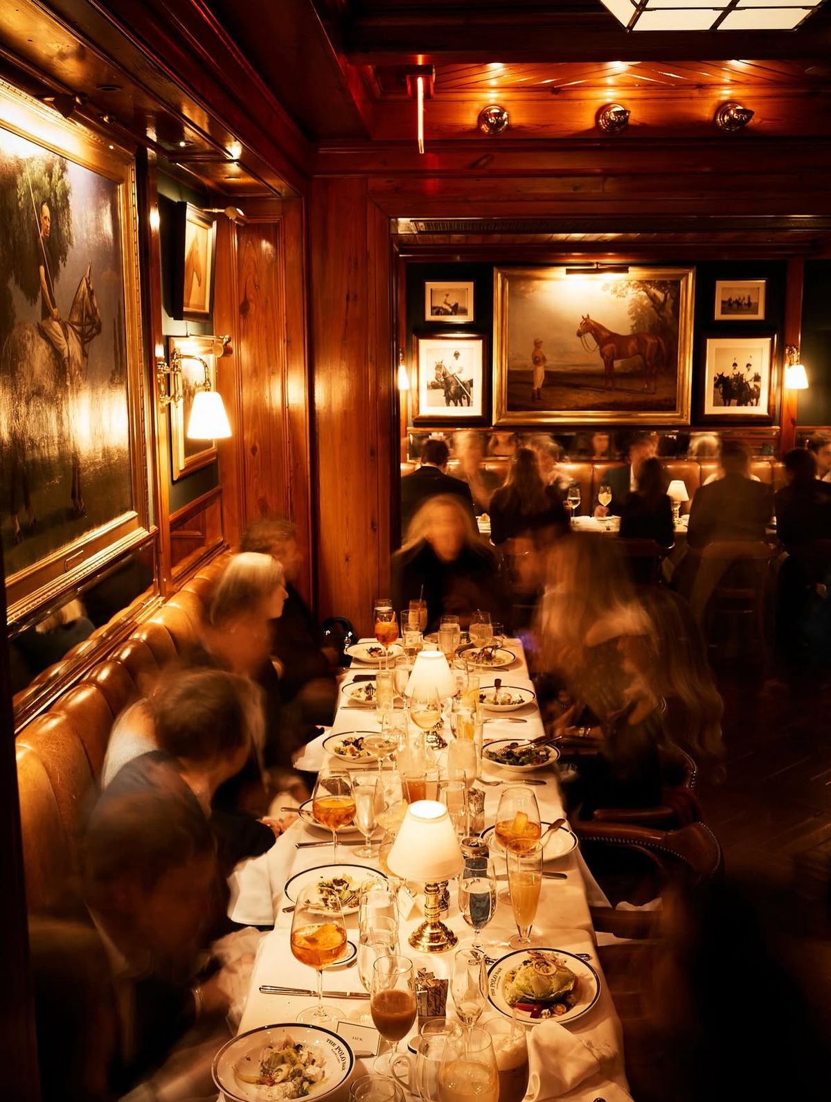 Lange Dinnertafel bei Kerzenlicht in einem holzgetäfelten Restaurant